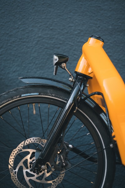 黑色自行车车轮旁边黄色塑料容器
